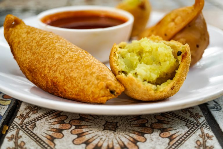 A samosa and an aloo bhajji broken open, with chutney